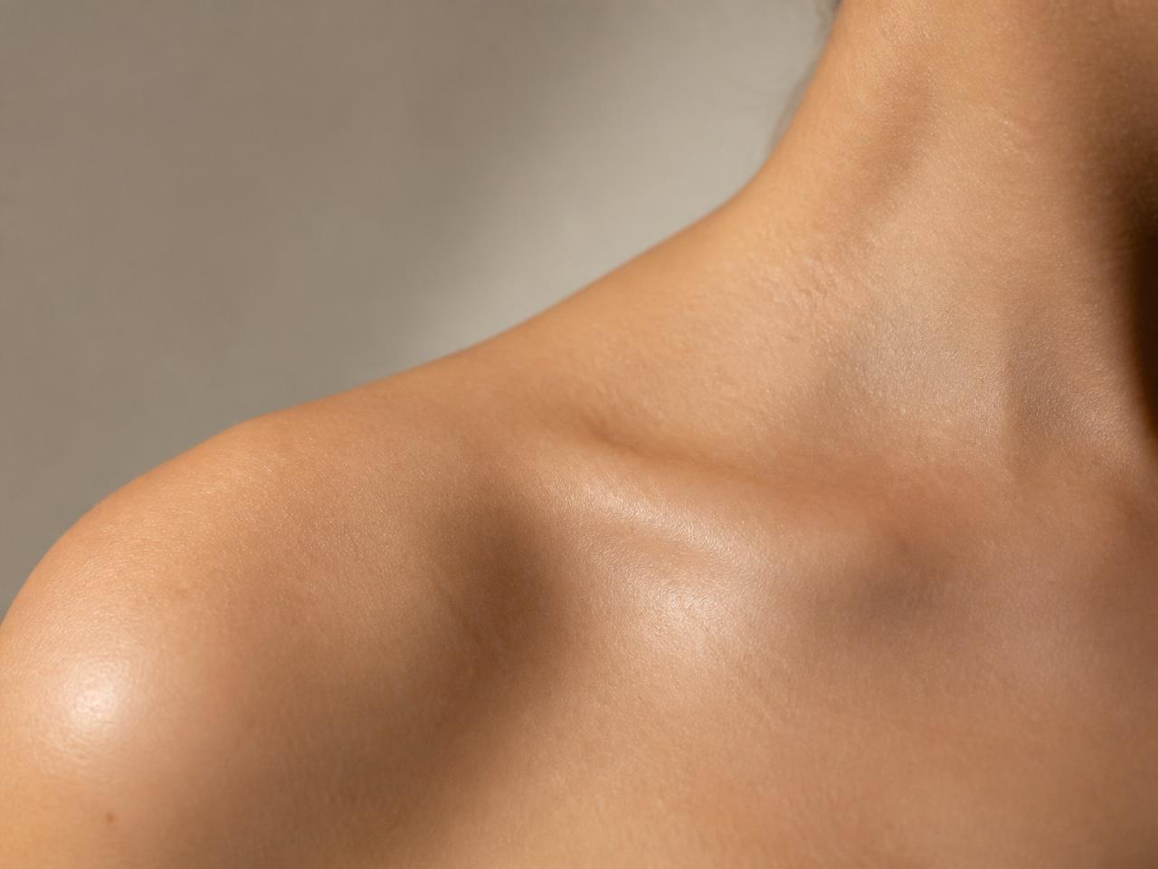 Close-up of neutral, healthy skin texture across a shoulder in soft daylight